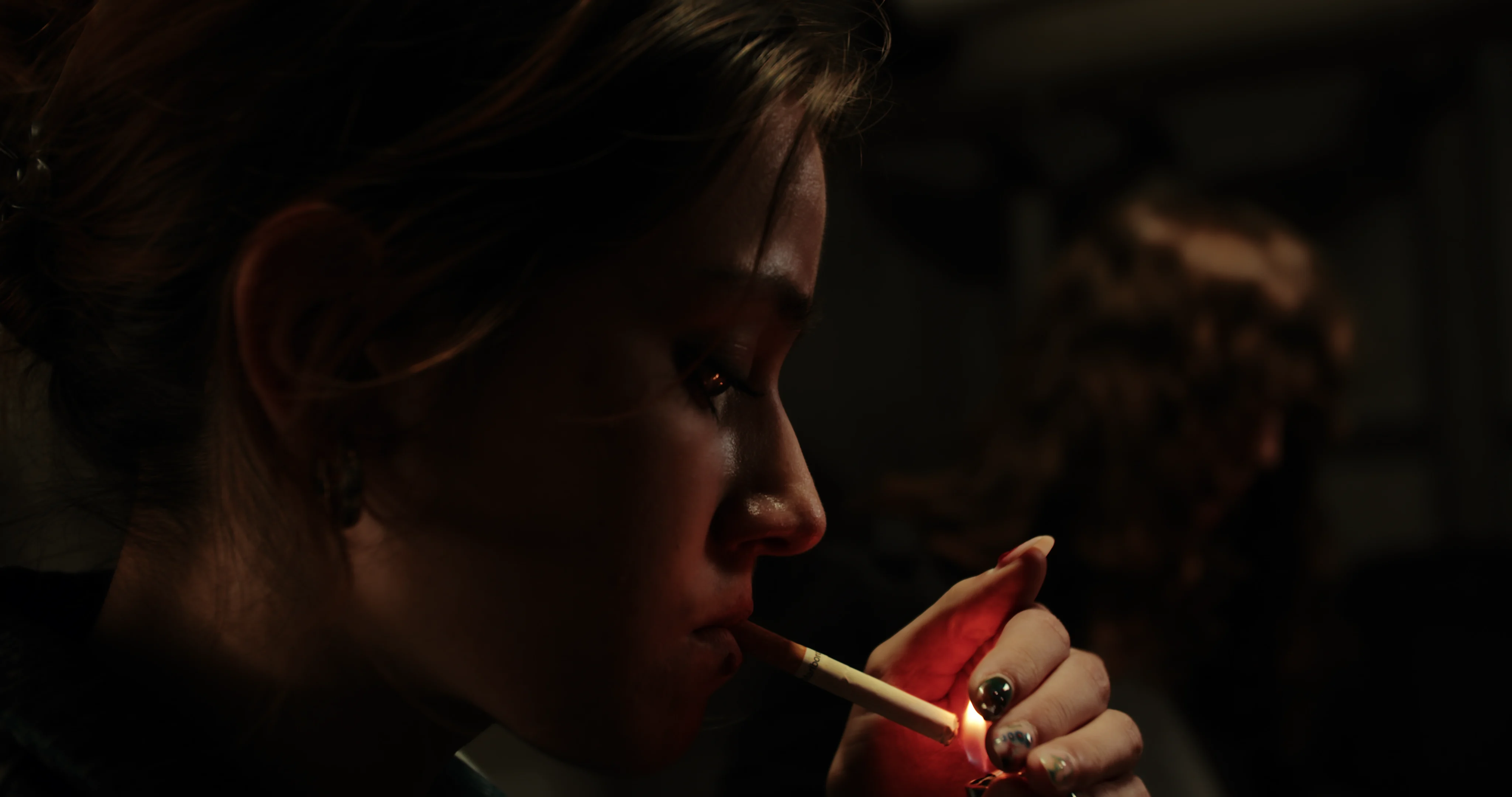 A woman in a dark room, seen in profile.