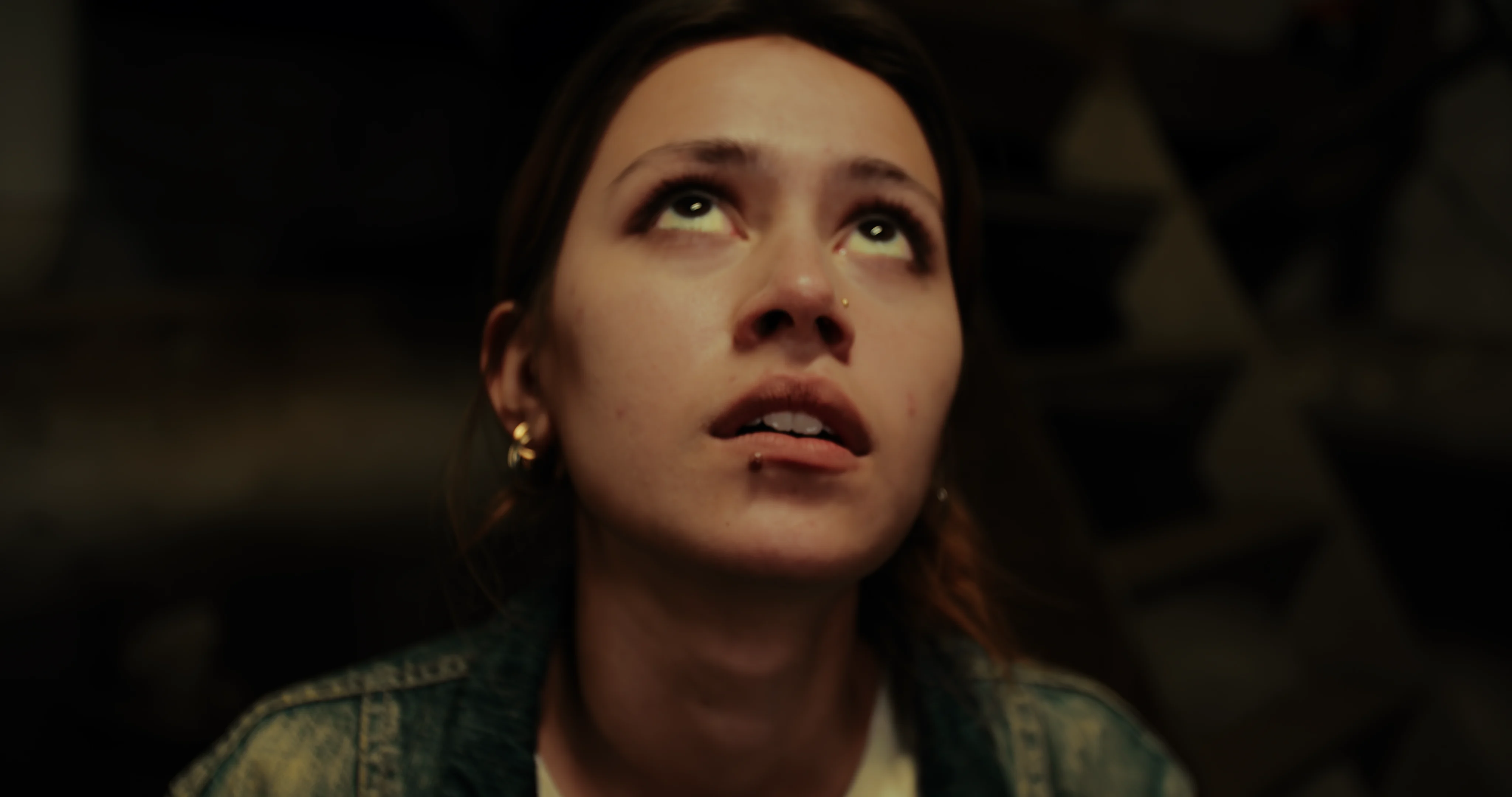 A woman looks upward toward a source of light.