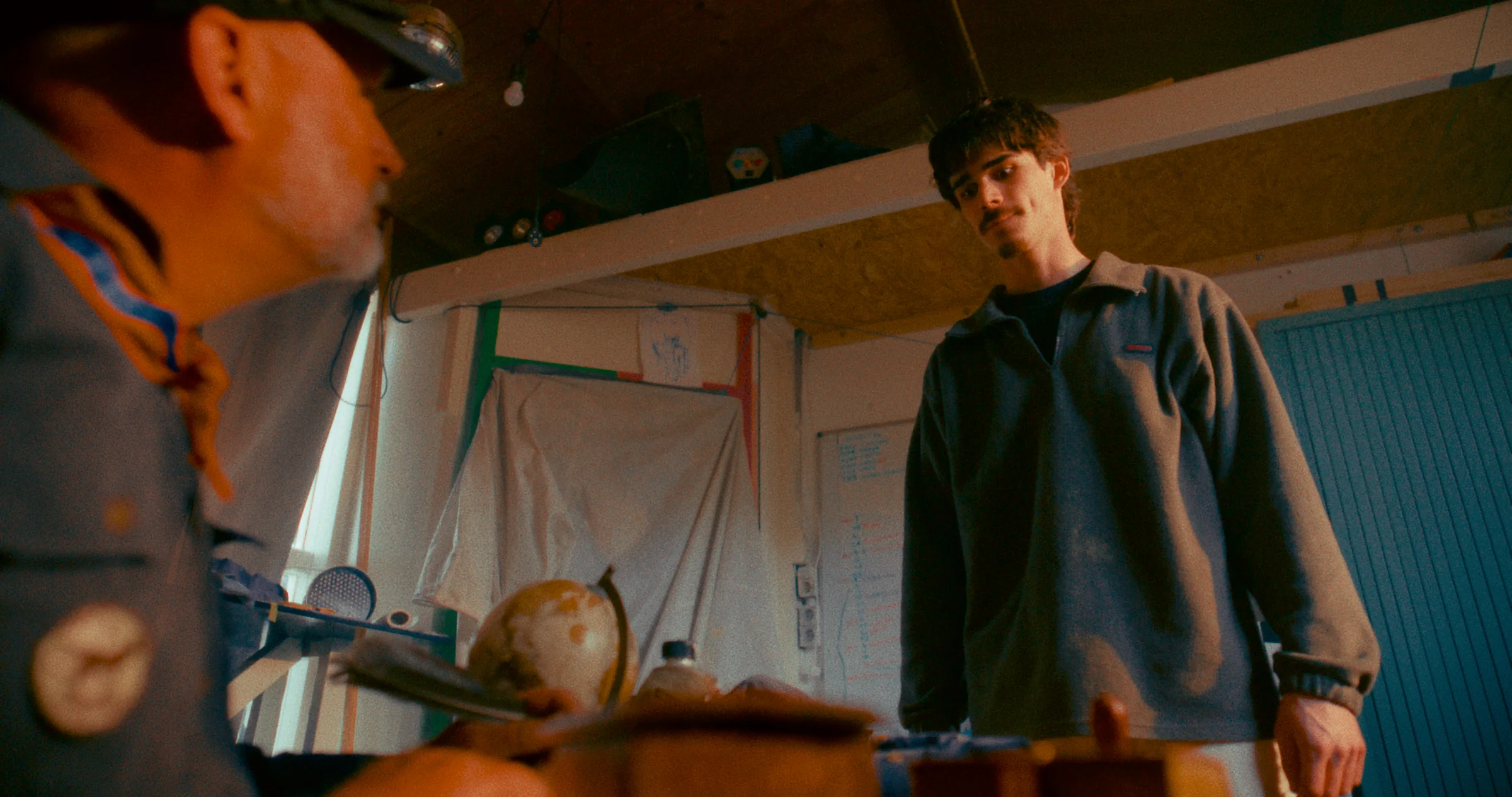 Two people stand in a warmly lit room.
