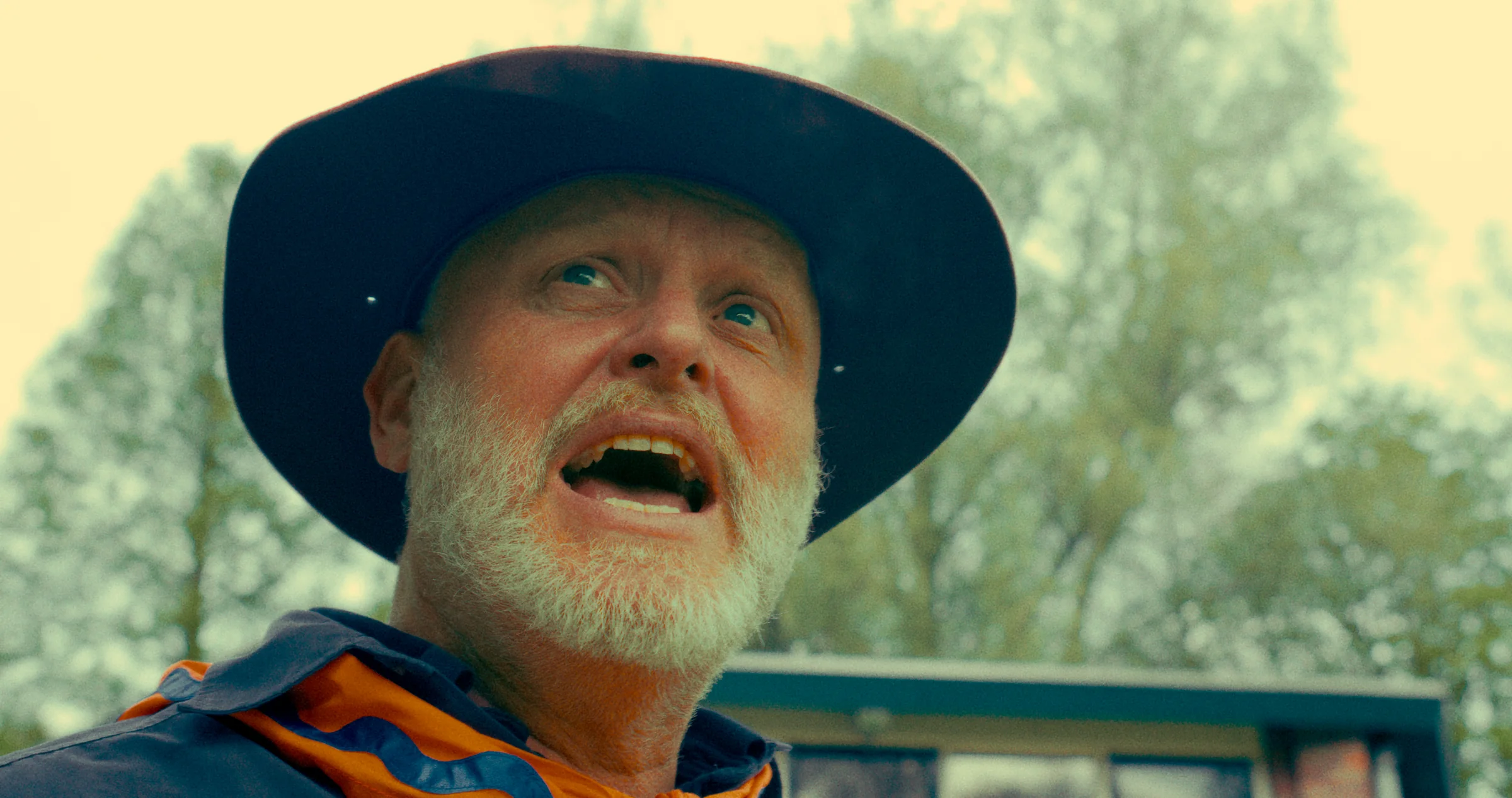 An older man wears a dark hat outdoors.