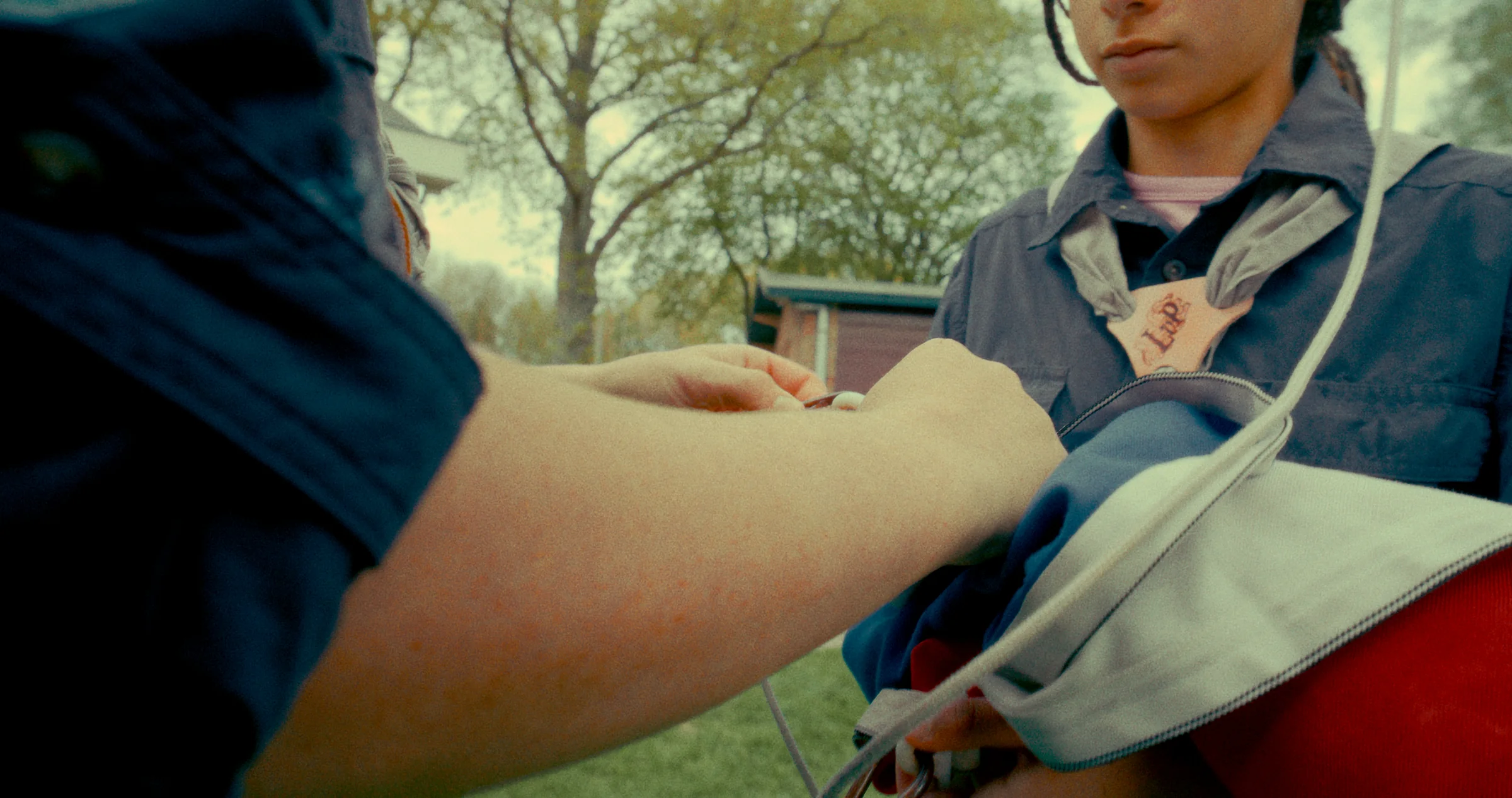 A person with a backpack is framed from the chest down as another hand reaches toward their jacket.