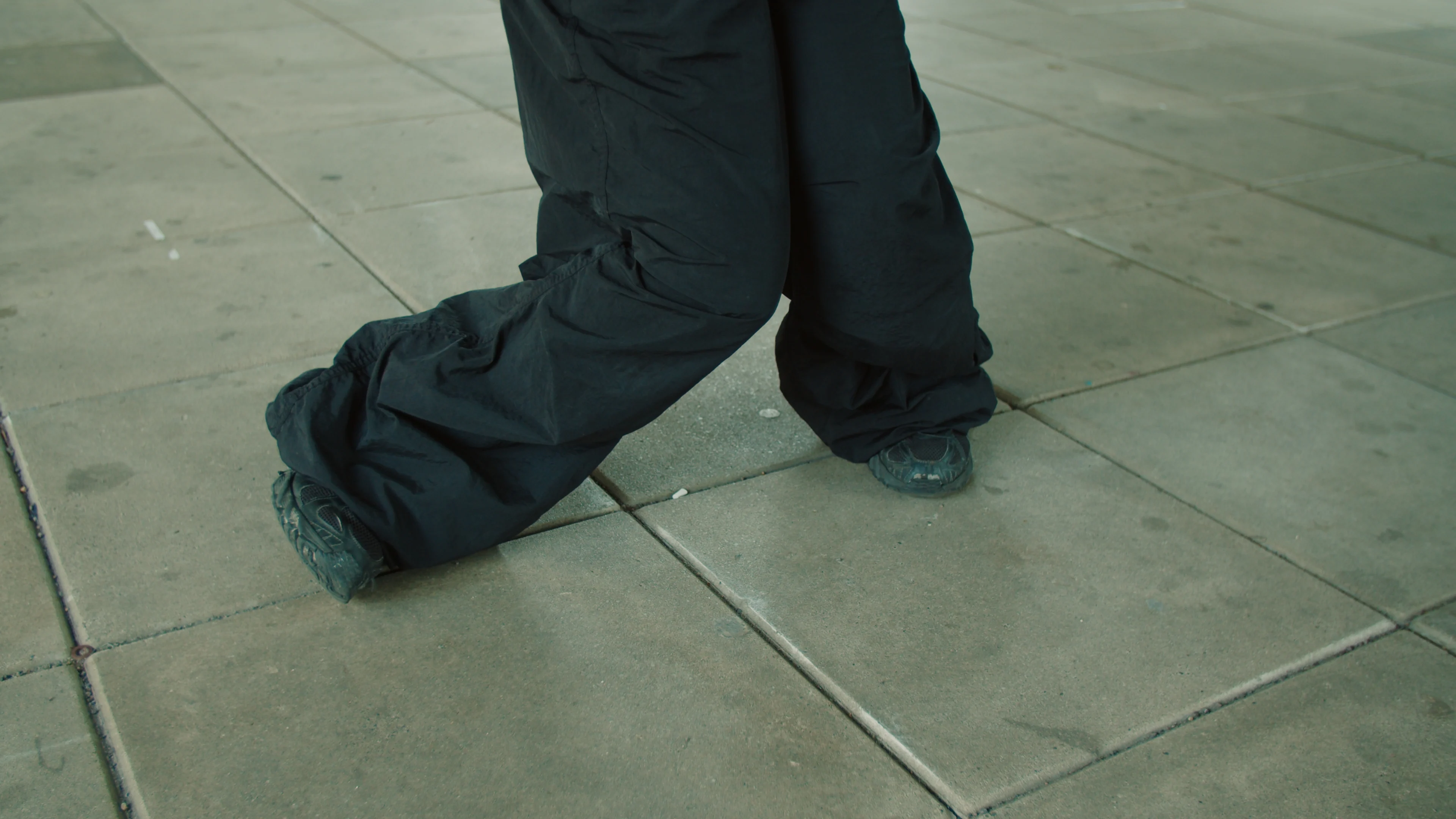 A quiet detail of footsteps on a tiled floor.