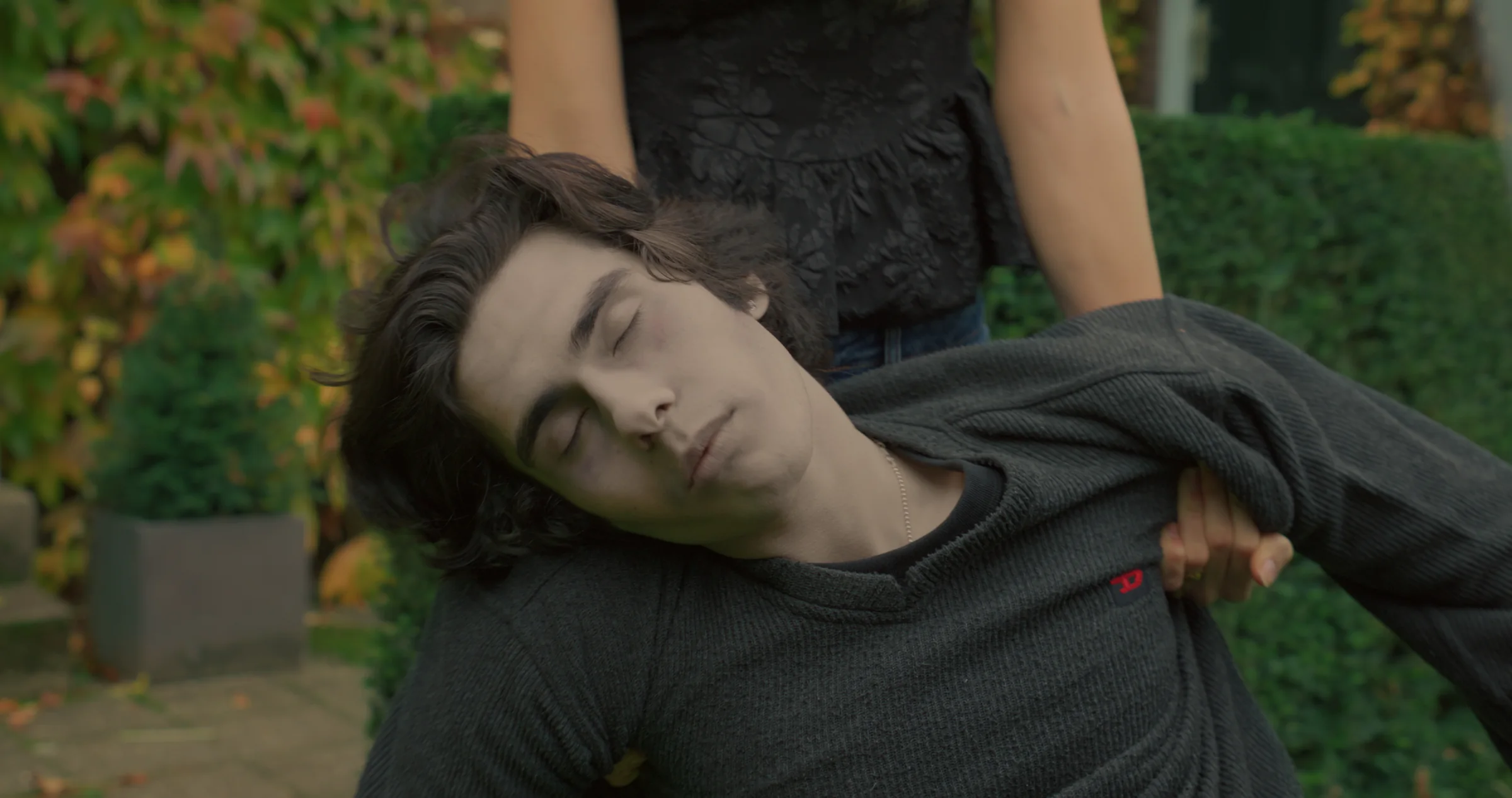 A man lies in a wooded outdoor setting.