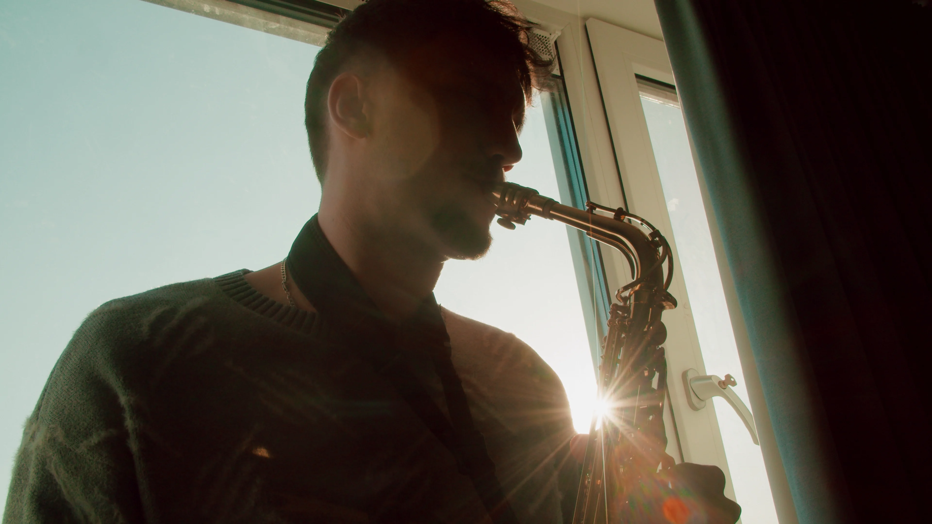 A saxophonist plays in a warmly lit room.