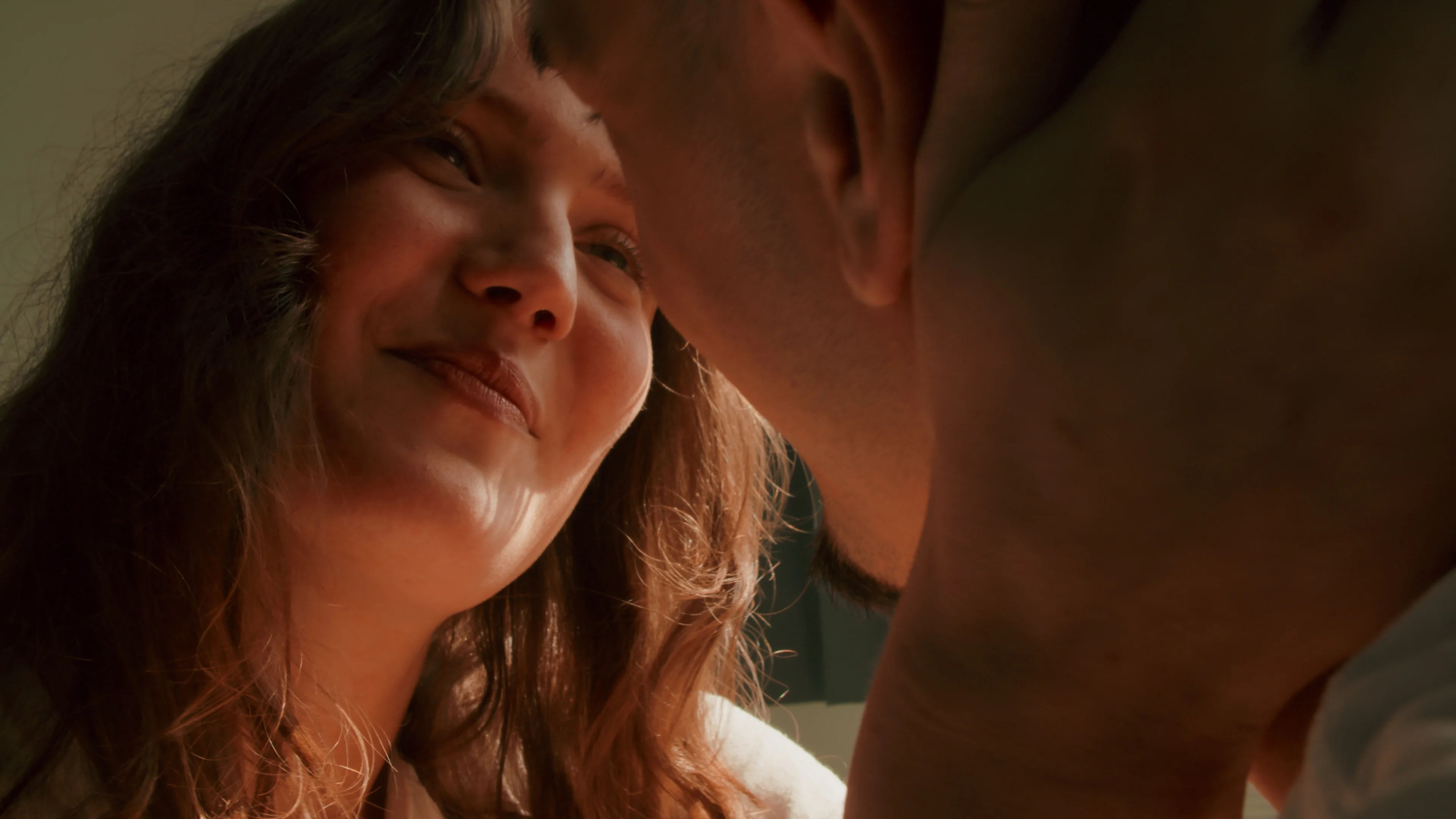 A couple smile together in soft amber light.